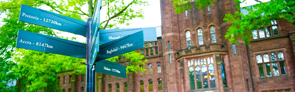 Sign on campus pointing to different cities across the world and distance away.